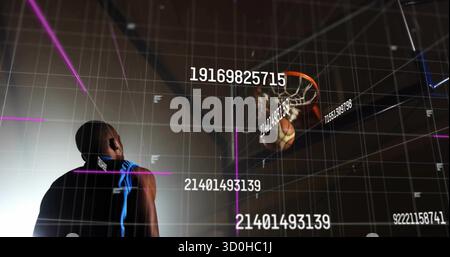 Athlète masculin debout en maillot, balle de suivi entrant dans le cerceau de la salle de gym, avec superpositions de grille de données Banque D'Images