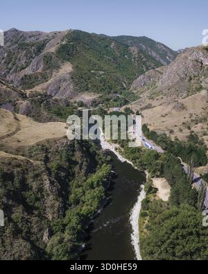 Vue aérienne de la rivière sinueuse sculpte à travers des montagnes escarpées, ses eaux sombres contrastent fortement avec les pentes ensoleillées, Samtskhe-Javakheti, Samtskhe-Javakheti, Géorgie. Banque D'Images