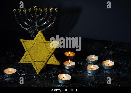 Étoile de David, bougies et menorah sur fond noir texturé. Concept de l'Holocauste. Banque D'Images
