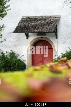 Porte de chapelle en bois rouge antique avec cadre en pierre voûtée et auvent en bardeaux. Banque D'Images