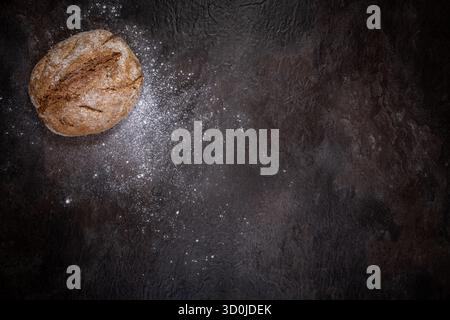 Épeautre rond de levain entier pain complet sur une surface en ardoise foncée, en haut à gauche. Le reste du cadre laisse beaucoup d'espace vide pour le texte Banque D'Images