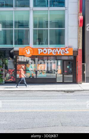 Un homme marchant près du restaurant de restauration rapide Popeyes Banque D'Images
