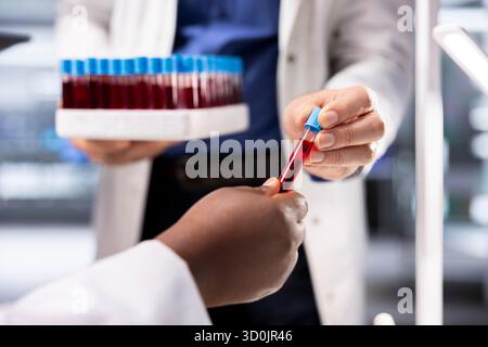 Gros plan de chercheurs recueillant des échantillons de sang dans des flacons sur plateau, la procédure de manipulation avec des tubes à essai en laboratoire. Équipe d'experts menant des expériences diagnostiques et biologiques. Banque D'Images