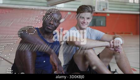 Hommes athlétiques au repos prenant une pause sur le terrain de basket-ball gymnase en bois, avec cerceau et rembourrage mural Banque D'Images