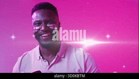 Homme noir en chemise rose tenant le ballon de football portant le drapeau de l'Angleterre facepaint sur le studio magenta set Banque D'Images