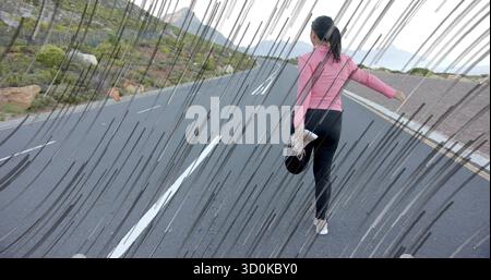Étirer femme asiatique dans l'équipement athlétique tirant le pied derrière sur la route de montagne, avec casquette et chaussure Banque D'Images