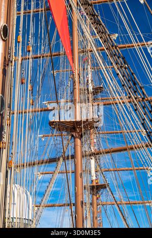 Grand voilier vintage avec voile rouge et gréement complexe contre le ciel bleu Banque D'Images