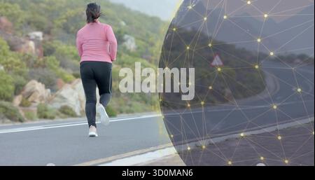 Femme de jogging portant un haut rose et des leggings noirs sur une route de montagne pavée, avec superposition en maille numérique Banque D'Images