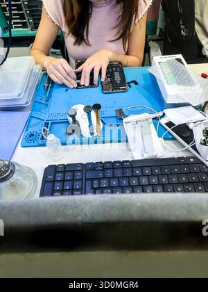 Technicien réparant un smartphone avec divers outils sur un établi dans un atelier de réparation électronique magasin palma mallorca Banque D'Images