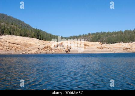 Bas niveau d'eau du réservoir avec des roches exposées et un ciel bleu clair Banque D'Images