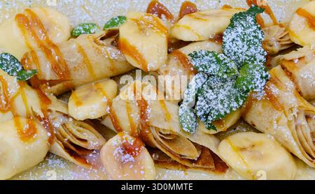 crêpes fraîchement cuites décorées de sauce banane et caramel sur assiette blanche. Photo de haute qualité Banque D'Images