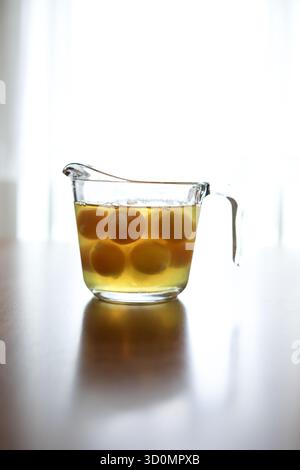 Tasse à mesurer en verre plein d'oeufs crus se trouve sur une table en bois Banque D'Images