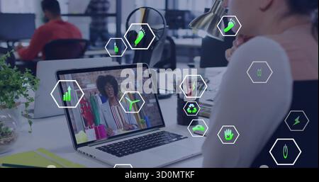 Regarder un employé portant un haut léger se concentrant sur l'écran d'ordinateur portable dans le bureau avec des icônes de durabilité Banque D'Images