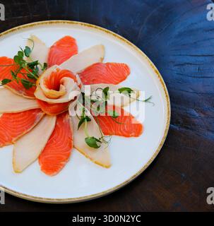 une grande assiette de saumon tranché et des morceaux de papillons. Garni d'herbes et de tranches de citron. apéritif froid à partir de précieuses espèces savoureuses de poissons marins. Photo de haute qualité Banque D'Images