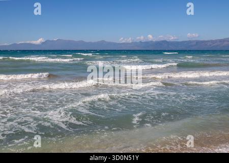 Mer Ionienne avec des vagues spectaculaires pendant une journée d'été tardive. Montagnes albanaises en arrière-plan. Ciel bleu avec des nuages blancs. Nord de l'île Corfou ( Banque D'Images