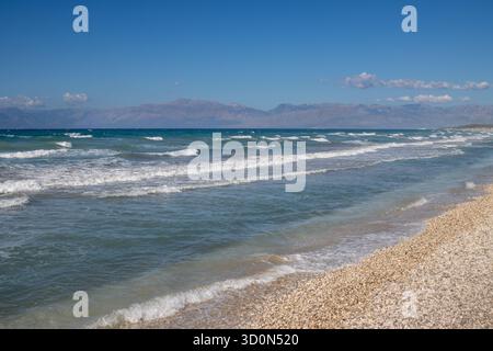Mer Ionienne avec des vagues spectaculaires pendant une journée d'été tardive. Montagnes albanaises en arrière-plan. Ciel bleu avec des nuages blancs. Nord de l'île Corfou ( Banque D'Images
