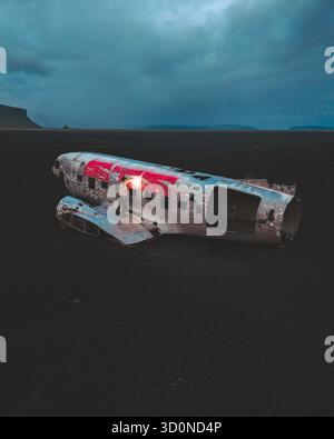 Vue aérienne de l'épave de l'avion DC-3 altérée reposant sur le sable noir et dur sous le ciel spectaculaire, l'épave de l'avion Solheimasandur, Mýrdalshreppur, Islande. Banque D'Images