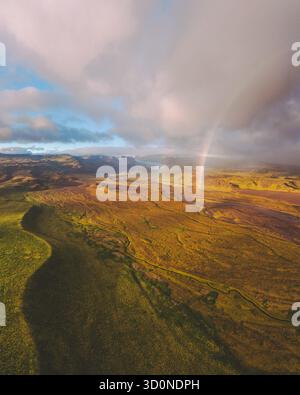 Vue aérienne d'un arc-en-ciel vibrant s'étendant sur les paysages spectaculaires du glacier Sólheimajökull, ses couleurs contrastent fortement avec le terrain accidenté, Sólheimajökull, Mýrdalshreppur, Islande. Banque D'Images