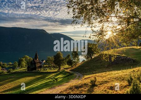 Urnes, Norvège - 24 août 2025 : village d'Ornes et l'église historique des urnes Stave sur le Lustrafjorden en Norvège au coucher du soleil Banque D'Images
