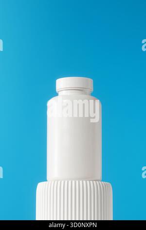 Mockup est un pot blanc avec des pilules ou des vitamines sur un podium sur un fond bleu. Le concept de préparations médicales. Banque D'Images