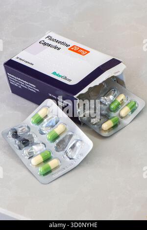 Boîte et plaquette thermoformée de comprimés antidépresseurs de fluoxétine de couleur verte et jaune ouverts sur une surface blanche unie. Les médicaments antidépresseurs de la fluoxétine Banque D'Images