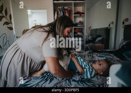 Une mère joue avec son bébé sur le lit dans une chambre confortable à la maison Banque D'Images