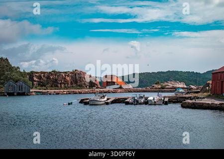 Une rangée de chalets colorés avec des bateaux amarrés à l'intérieur, reflétant sur l'eau calme. Banque D'Images