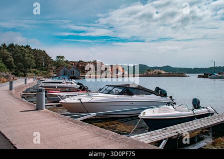 Une rangée de chalets colorés avec des bateaux amarrés à l'intérieur, reflétant sur l'eau calme. Banque D'Images