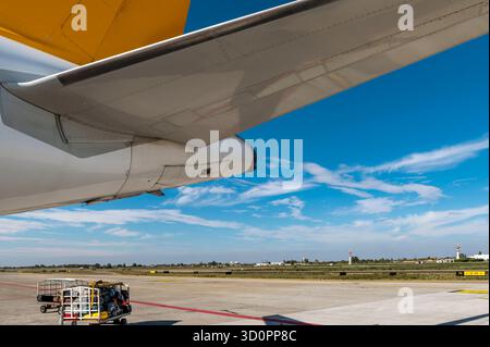Les bagages sont sur le point d'être chargés sur un vol au départ d'un aéroport, contre un ciel bleu avec des nuages blancs Banque D'Images