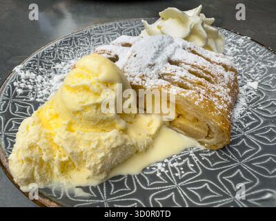 Une tranche de strudel de pomme avec de la crème fouettée fraîche et de la glace à la vanille Banque D'Images