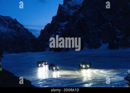 Bichkek, Kirghizistan - 13 décembre 2024 : vue à angle bas de plusieurs VUS 4x4 conduisant ou s'arrêtant sur la surface rugueuse et réfléchissante d'un lac gelé, Ill Banque D'Images