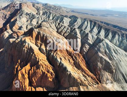Vue aérienne à grand angle d'un vaste paysage complexe montrant des schémas parallèles complexes d'érosion à travers des pentes de roches rouges, oranges et grises Banque D'Images