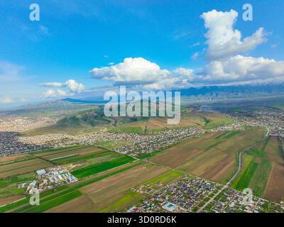 Bichkek, Kirghizistan - 13 mai 2024 : vue aérienne panoramique de la périphérie de la ville de Bichkek et des terres agricoles rencontrant des contreforts verdoyants, avec le mou enneigé Banque D'Images