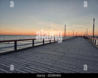 Un beau coucher de soleil sur la mer Baltique, vu depuis la jetée en bois emblématique de Palanga, Lituanie. Banque D'Images