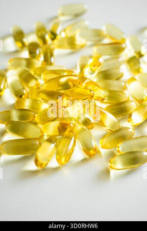 Capsules molles jaune vif sur surface blanche à la lumière du soleil Banque D'Images