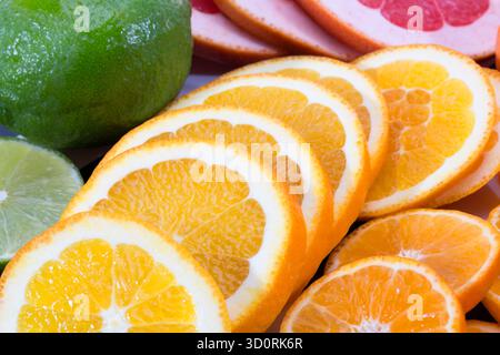 Arrière-plan de tranches de fruits de pamplemousse rouge, de citron vert et de mandarine, gros plan Banque D'Images