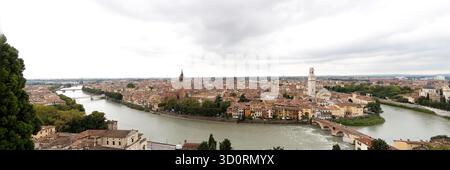 Vue panoramique de Vérone avec la rivière Adige, les bâtiments historiques et les tours d'église sous un ciel nuageux spectaculaire, Vénétie, Italie. Banque D'Images