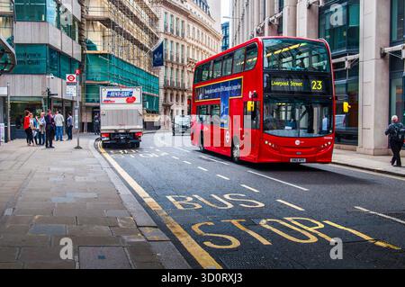 Bus à impériale rouge passant près d'un camion garé près d'un arrêt de bus dans une rue de Londres. Banque D'Images