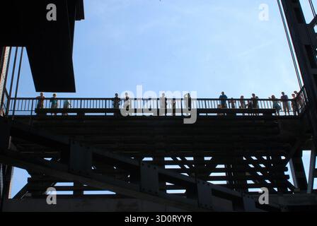 Silhouettes de touristes et de visiteurs sur un pont surélevé ou une plate-forme d'observation de l'ascenseur à bateaux de Niederfinow contre un ciel bleu lumineux. Banque D'Images