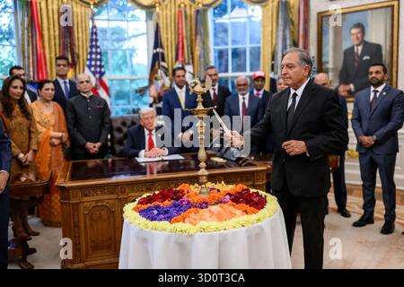 Un invité allume la lampe de cérémonie Diya pendant la célébration de Diwali dans le bureau ovale de la Maison Blanche, Washington, DC, le 21 octobre 2025. Le président Donald J. Trump et des responsables amérindiens observent la cérémonie marquant la Fête des lumières, honorant la culture et la tradition indiennes. Image reproduite avec l'aimable autorisation de la Maison Blanche. Banque D'Images