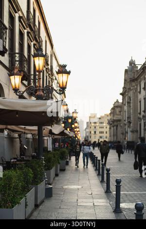 Scène de rue au coucher du soleil dans le centre historique de Lima, Pérou, 2024. Les piétons marchent le long d'une rue coloniale bordée de cafés et de vieux bâtiments. Banque D'Images