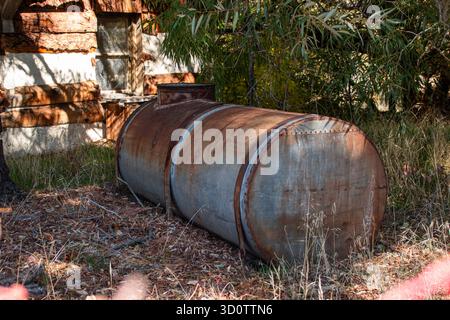 Un vieux réservoir en métal galvanisé utilisé pour le stockage de l'eau près d'une cabane abandonnée dans les bois. Banque D'Images