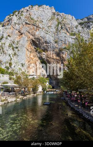 Restaurants à côté des eaux cristallines de la rivière Buna près de Mostar, avec le magnifique Blagaj Tekke, un monastère derviche, en arrière-plan. Banque D'Images