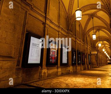 Vue en perspective du couloir extérieur de l'Opéra national de Vienne (Wiener Staatsoper) avec lumières allumées et publicités Banque D'Images