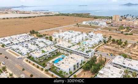 Vue aérienne d'un quartier résidentiel côtier moderne avec maisons contemporaines blanches et complexes d'appartements avec piscines, palmiers et gree Banque D'Images