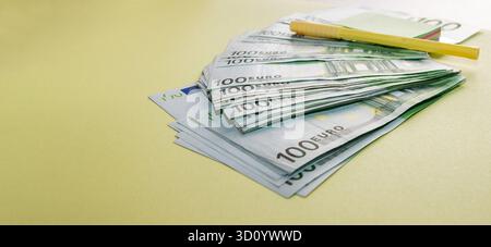 Pile de cent billets en euros avec stylo jaune et bloc-notes symbolisant la planification financière et le succès commercial Banque D'Images