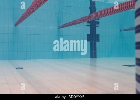 Vue sous-marine d'une piscine vide avec des cordes rouges, des murs carrelés bleus et un fond carrelé clair. Banque D'Images