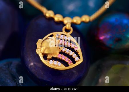 Bijoux en or pour enfants Dollar et chaîne – gros plan traditionnel Indien Kids Gold Ornament sur fond de pierre de couleur Banque D'Images