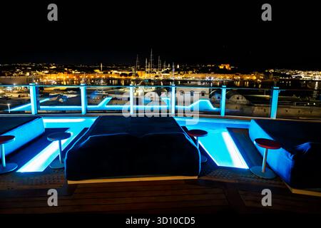 Vue en soirée depuis les piscines extérieures sur un bateau de croisière des murs illuminés, marina, vieille ville et château le long du port de Rhodes, Grèce. Banque D'Images