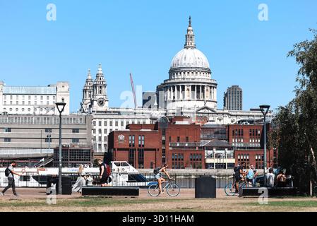 Londres, Angleterre - 11 août 2022 : le dôme de la cathédrale St Paul et les bâtiments de la Cité de Londres au bord de la rivière, les gens marchant et faisant du vélo le long de la Tamise embarquent Banque D'Images